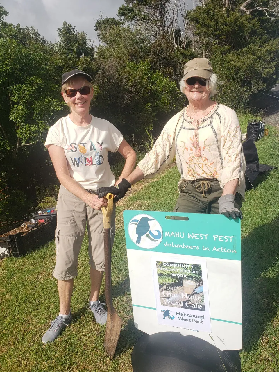 Two volunteers holding armfuls of pulled weeds at a weed café